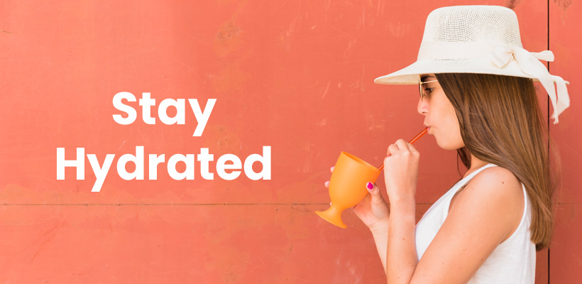 Young woman in hat holding cup and drinking fresh juices.