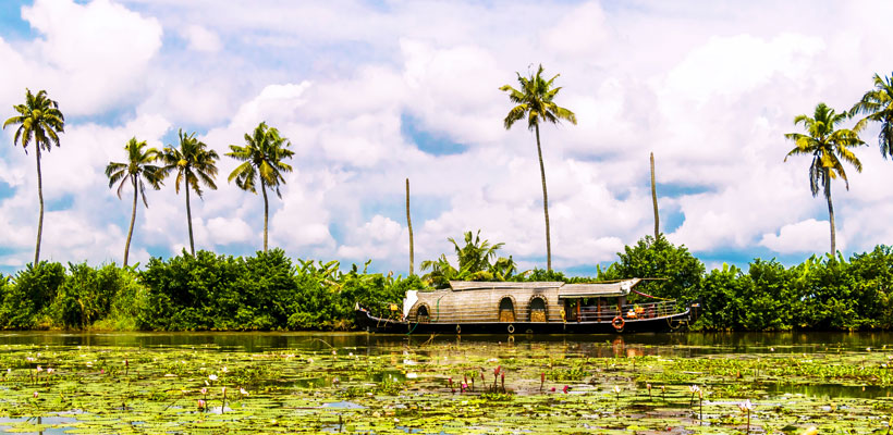 A charming view of houseboat sailing through the backwaters of Kumarakom in Kerala.